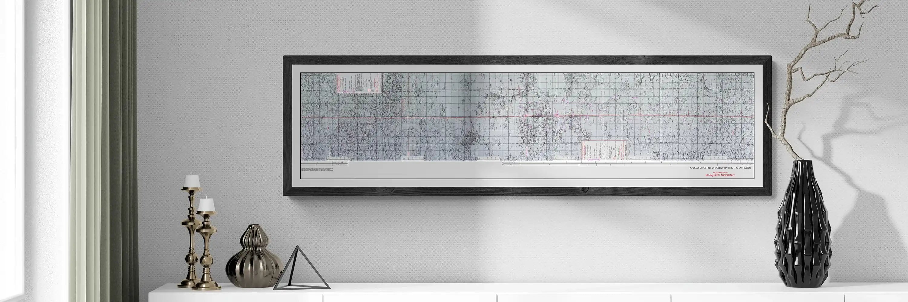Apollo 10 Lunar Map | Apollo 10 Moon Map | Rocket Blueprint Posters | The framed Apollo Target of Opportunity Flight Chart, showing detailed lunar topography with red navigation lines, hangs on a light-colored wall above a white table. The table holds three brass candlesticks, a metallic geometric piece, and a tall black vase with dried branches.