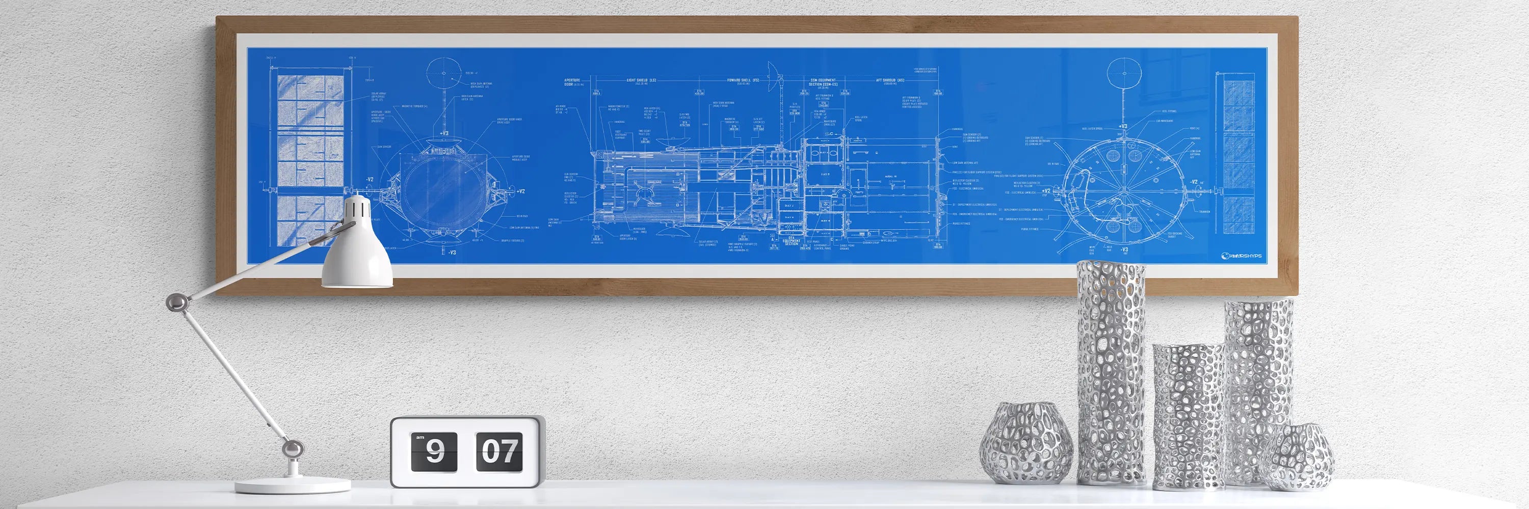 Hubble Space Telescope Blueprint | Rocket Blueprint Posters | The image shows a framed Hubble Space Telescope blueprint poster with intricate technical details, mounted on a light wall. Below, a white desk features a sleek white lamp, a flip clock reading 9:07, and a set of silver vases.