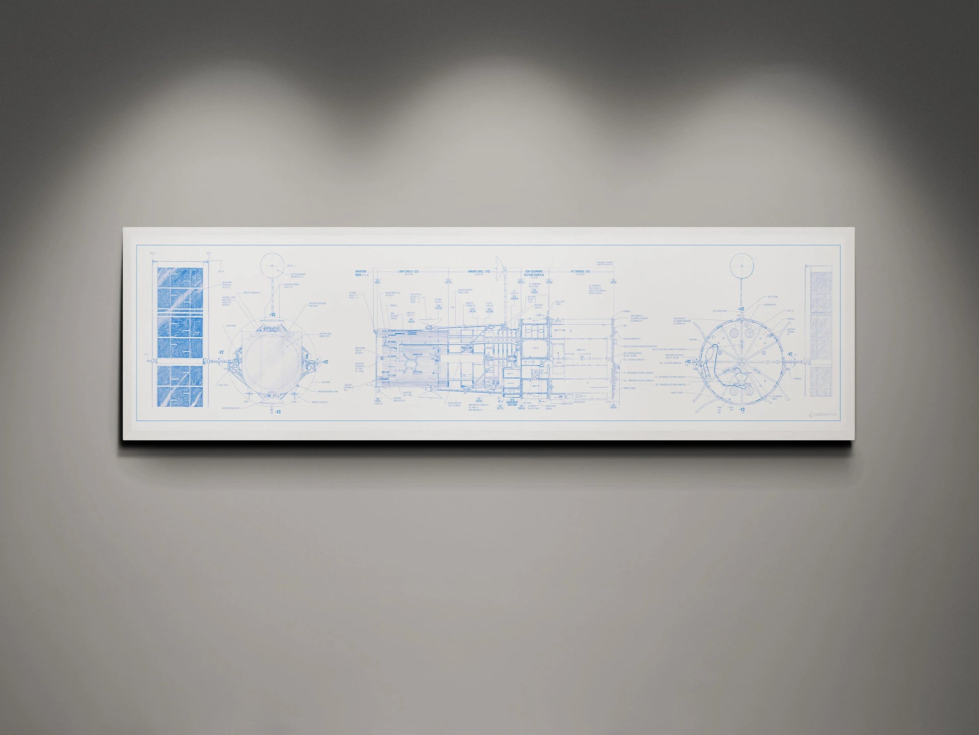 Hubble Space Telescope Blueprint | Rocket Blueprint Posters | A framed blueprint of the NASA Hubble Space Telescope, showcasing intricate technical drawings in blue on a white background. The blueprint is mounted on a gray wall and highlighted by soft overhead lights.