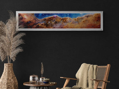 James Webb Space Telescope 'Cosmic Cliffs' panoramic poster framed and displayed in a modern, cozy interior with dark walls and natural decor elements. Space-themed art print for astronomy enthusiasts and stylish home or office decoration