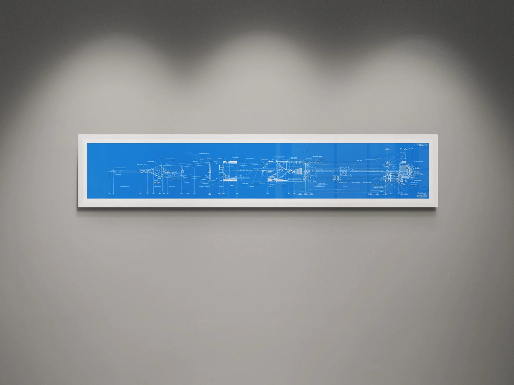 Apollo Saturn 1B Blueprint | NASA posters | Technical blueprint Diagram | A framed blueprint of the NASA Saturn IB rocket, showcasing intricate technical drawings in white on a blue background. The blueprint is mounted on a gray wall and highlighted by soft overhead lights.