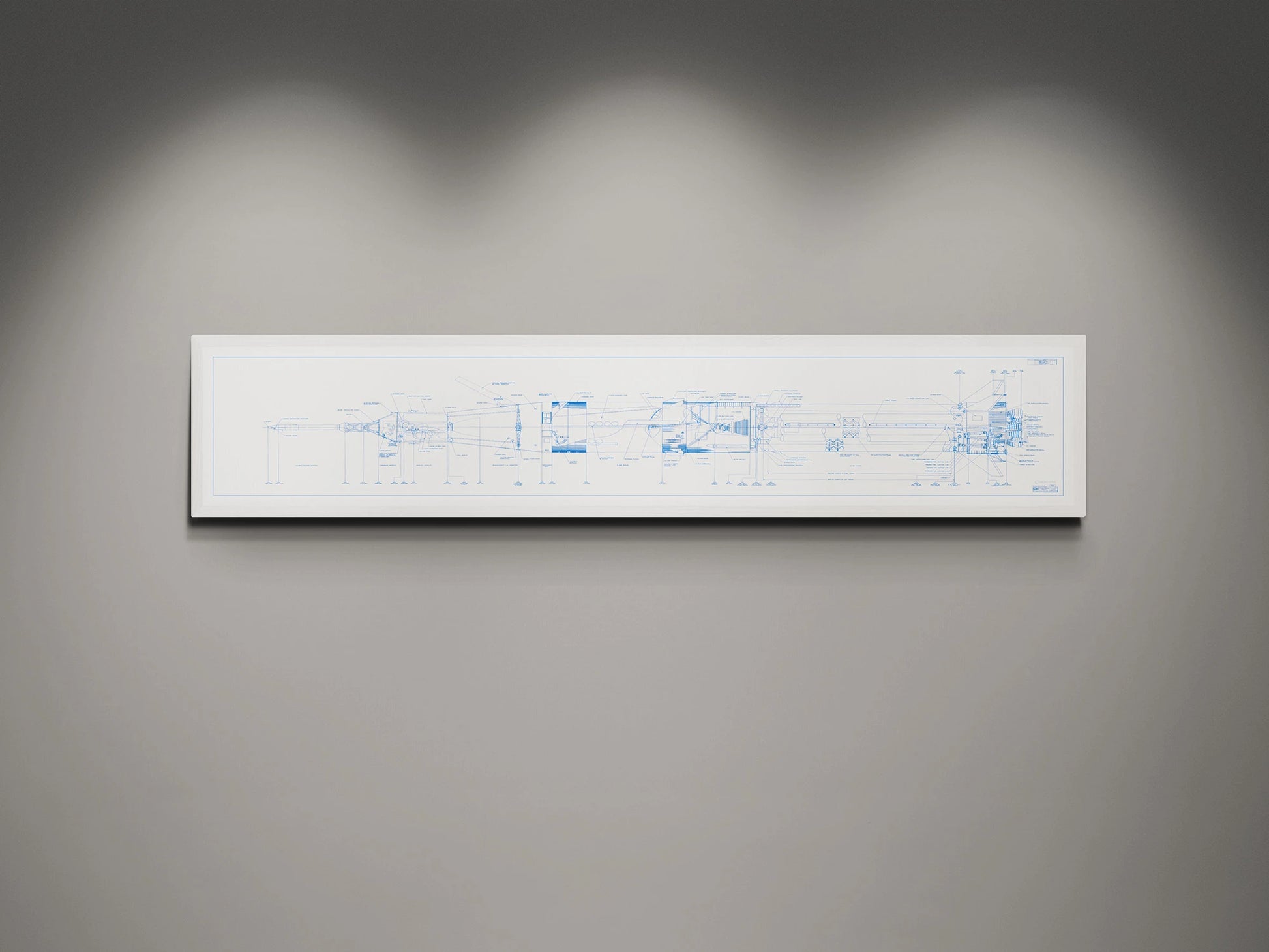 Apollo Saturn 1B Blueprint | NASA posters | Technical blueprint Diagram | A framed blueprint of the NASA Saturn IB rocket, displaying detailed technical drawings in blue on a white background. The blueprint is mounted on a gray wall and illuminated by subtle lighting from above.