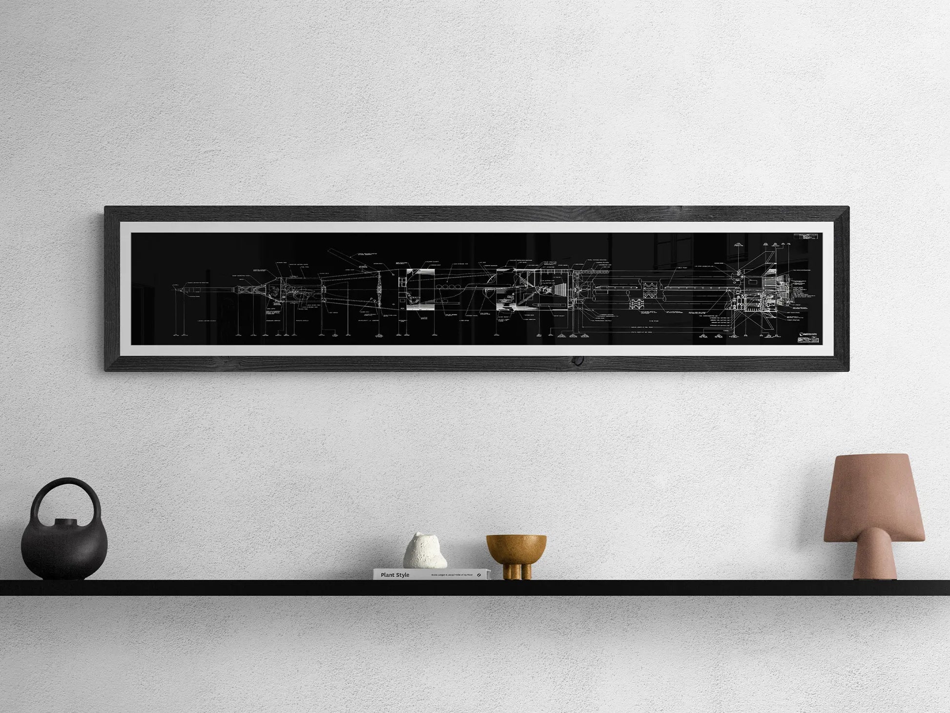 Apollo Saturn Blueprint | NASA posters | Technical blueprint diagram of an spacecraft | A framed black and white blueprint of the Saturn IB rocket hangs on a light gray wall above a black shelf. The shelf holds a round black teapot, a small white sculpture, a gold-colored bowl, and a small, brown lamp.