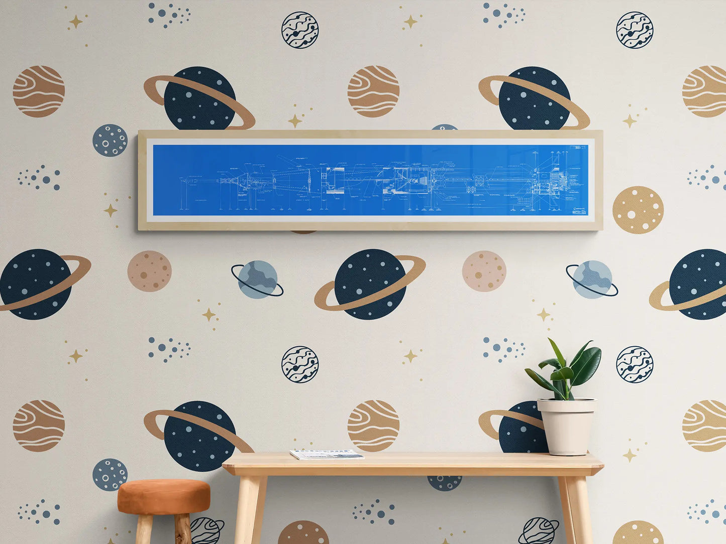 Apollo Saturn Blueprint | NASA posters | Technical blueprint diagram of an spacecraft | A bright blue-framed blueprint of the Saturn IB rocket is displayed on a wall with a space-themed wallpaper, featuring illustrations of planets, stars, and other celestial bodies. Below, a wooden table with a small potted plant and an orange cushioned stool complete the scene.