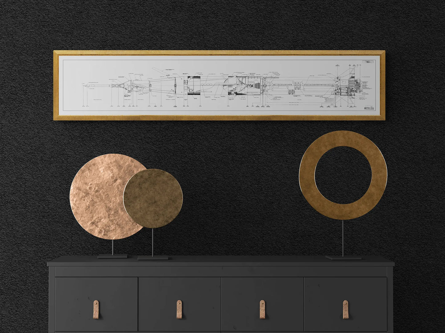 Apollo Saturn Blueprint | NASA posters | Technical blueprint diagram of an spacecraft | A minimalist interior featuring a black dresser with bronze handles. On top of the dresser are two circular metal sculptures, one solid and one with a central hole. Above the dresser, a gold-framed technical diagram of the NASA Saturn IB rocket is displayed against a dark textured wall.