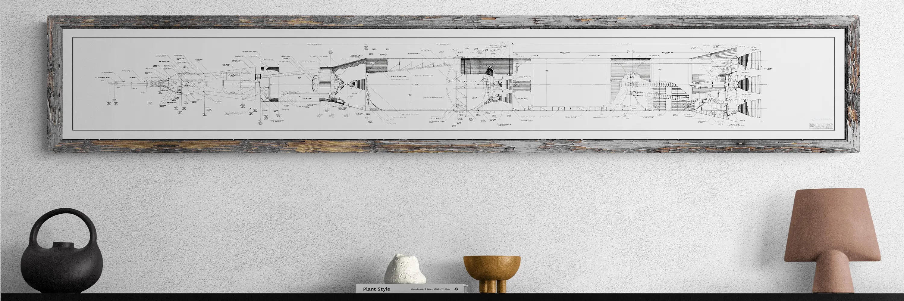 Apollo Saturn Blueprint | NASA posters | The framed Saturn V NASA blueprint, showing detailed technical drawings of the rocket, hangs on a light wall above a table. The table is decorated with a black teapot-shaped vase, a small white sculpture, a brass bowl, and a brown ceramic lamp, creating a modern and elegant look.